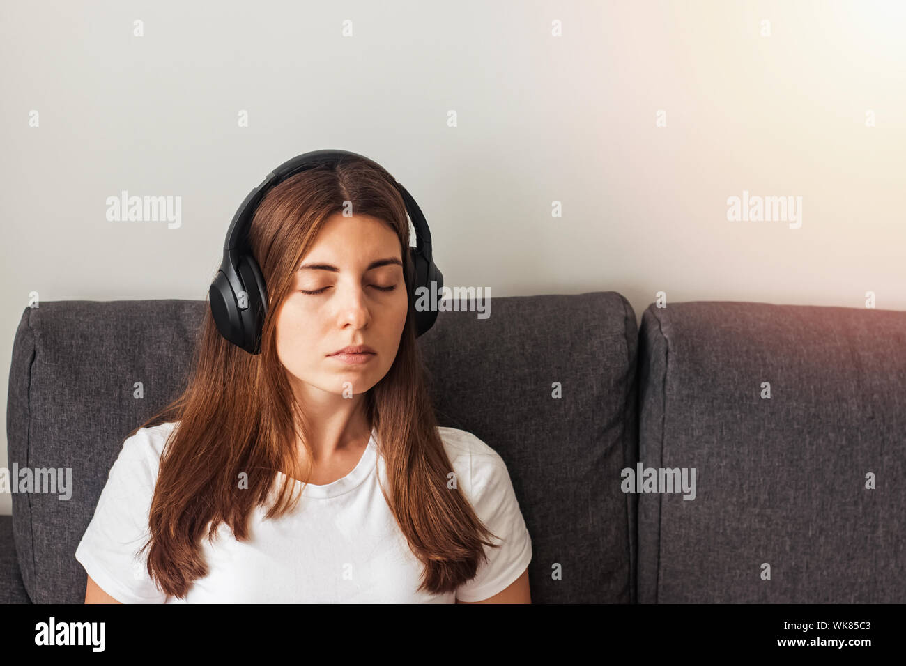 Young woman in big headphones listening to calm music or meditating Stock Photo