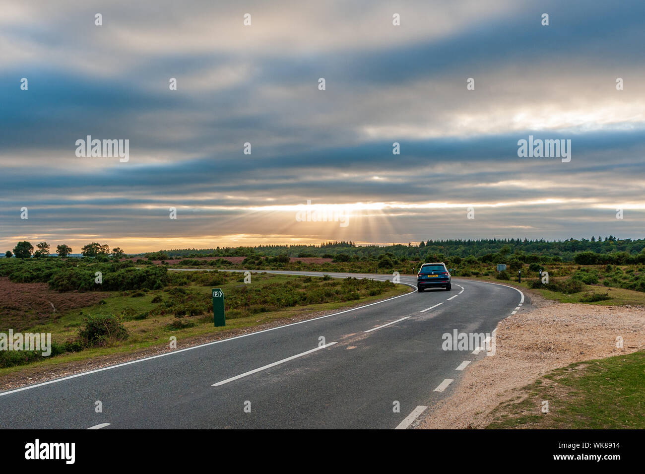 Motorist driving towards the setting sun on a late summer evening Deadman Hill, Godshill, New Forest, Hampshire Stock Photo