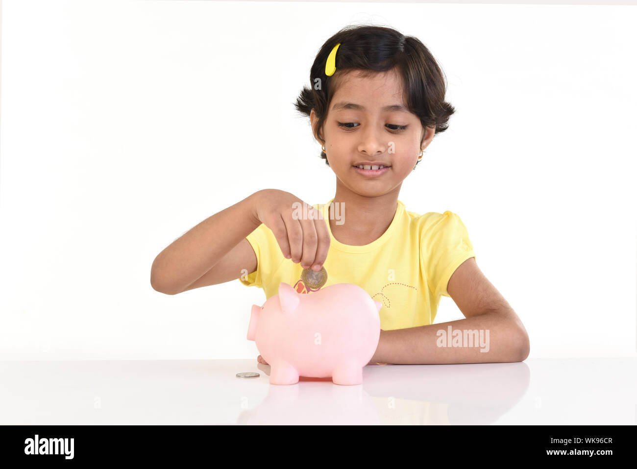 Girl putting a coin into a piggy bank Stock Photo - Alamy