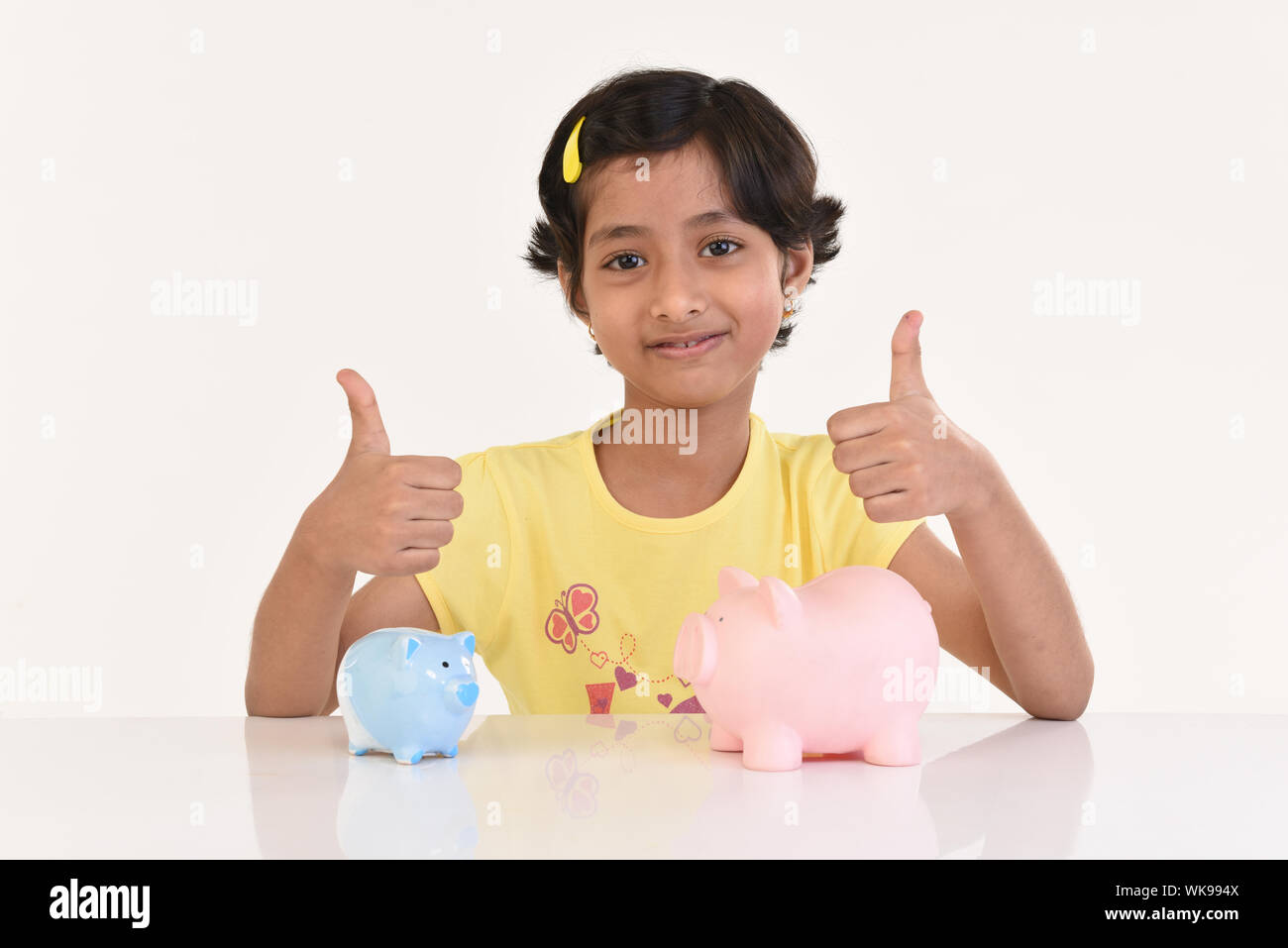 Girl sitting with piggy banks and showing thumbs up sign Stock Photo ...