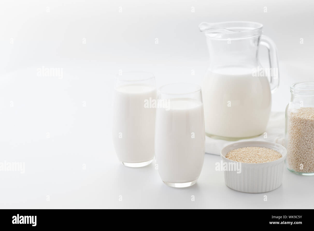 Organic white milk from sesame seeds in two glasses and in pitcher on the white background.Image in high key,selective focus.Calcium food.Horizontal. Stock Photo