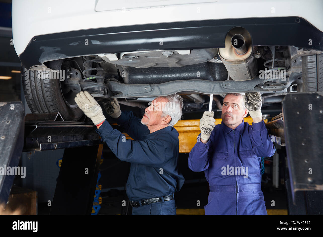 Two car mechanics or mechatronics inspect underbody protection on the car Stock Photo