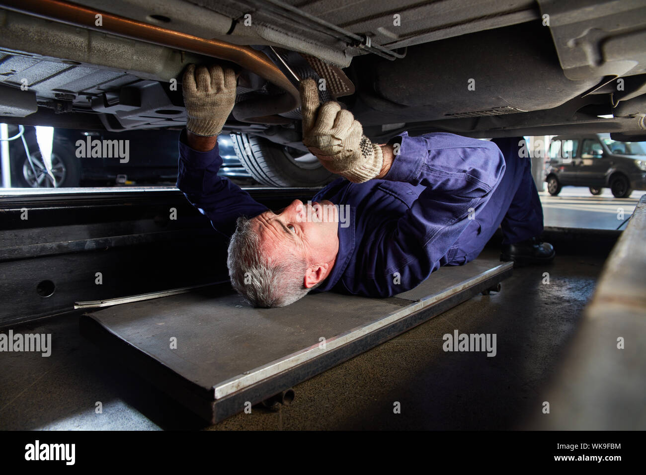 Experienced mechanic at the inspection or maintenance is under the car Stock Photo