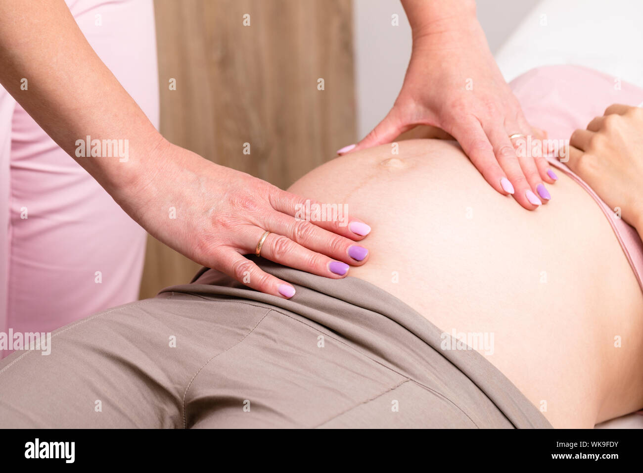 Close-up shot of obstetrician gynecologist manually examines pregnant woman's belly performing prenatal checkup Stock Photo
