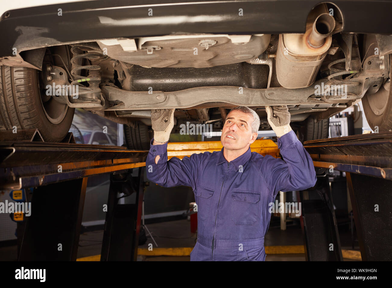Car mechanic at the inspection checks underbody protection of the car for corrosion Stock Photo