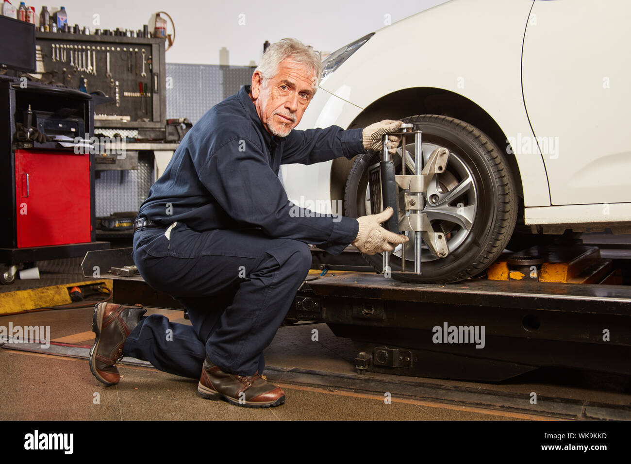 Experienced mechanic makes a wheel alignment in the auto repair shop Stock Photo