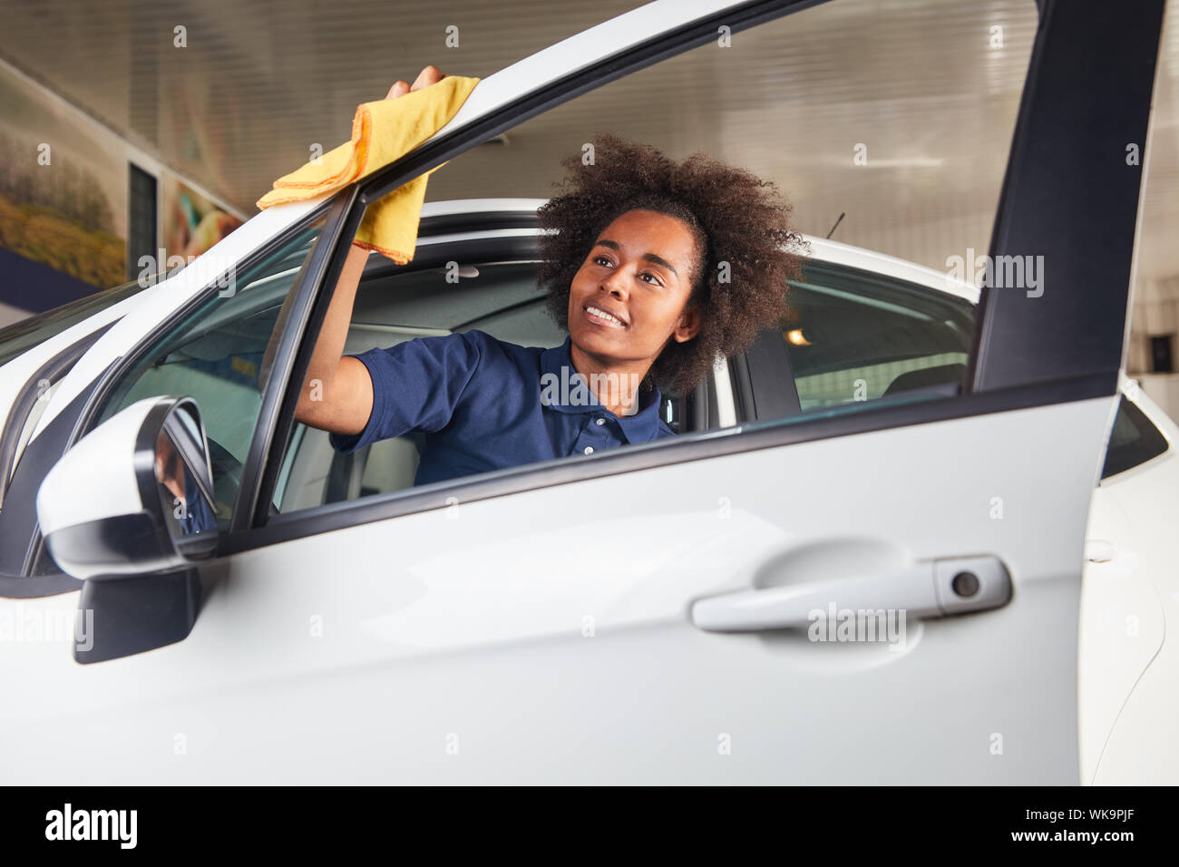African woman as a mechanic apprentice in the paint care of car in the dealership Stock Photo