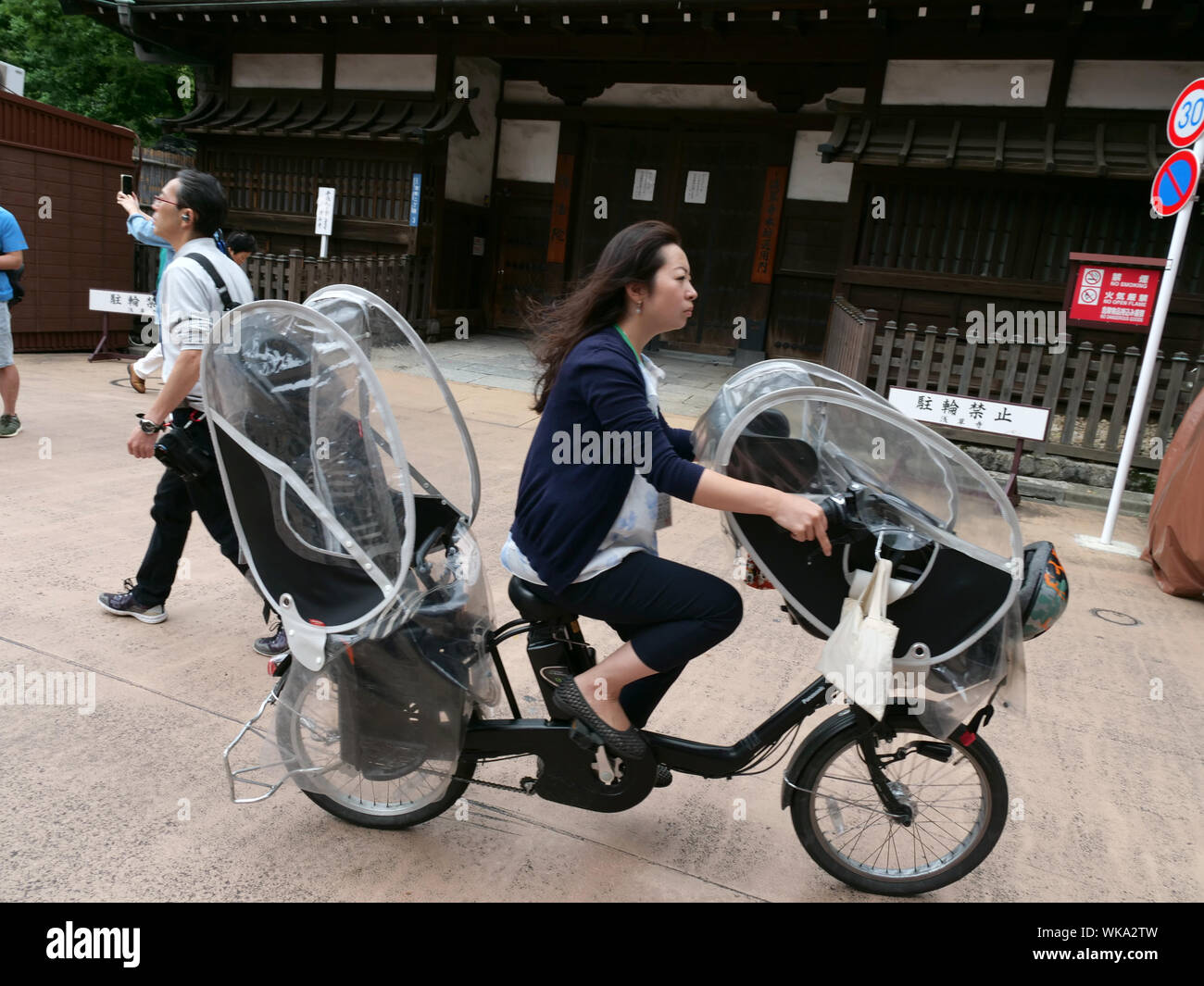JAPAN - photo by Sean Sprague  Asakusa, Tokyo. Woman riding bicycle with seats for two young children. Stock Photo