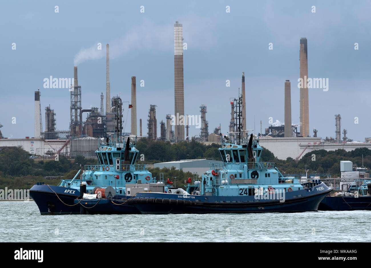 Fawley Marine, Southampton Water, England, UK. Apex and Phenix two Voith tractor tugs powered by Rolls Royce engines, alongside Fawley Marine refinery Stock Photo