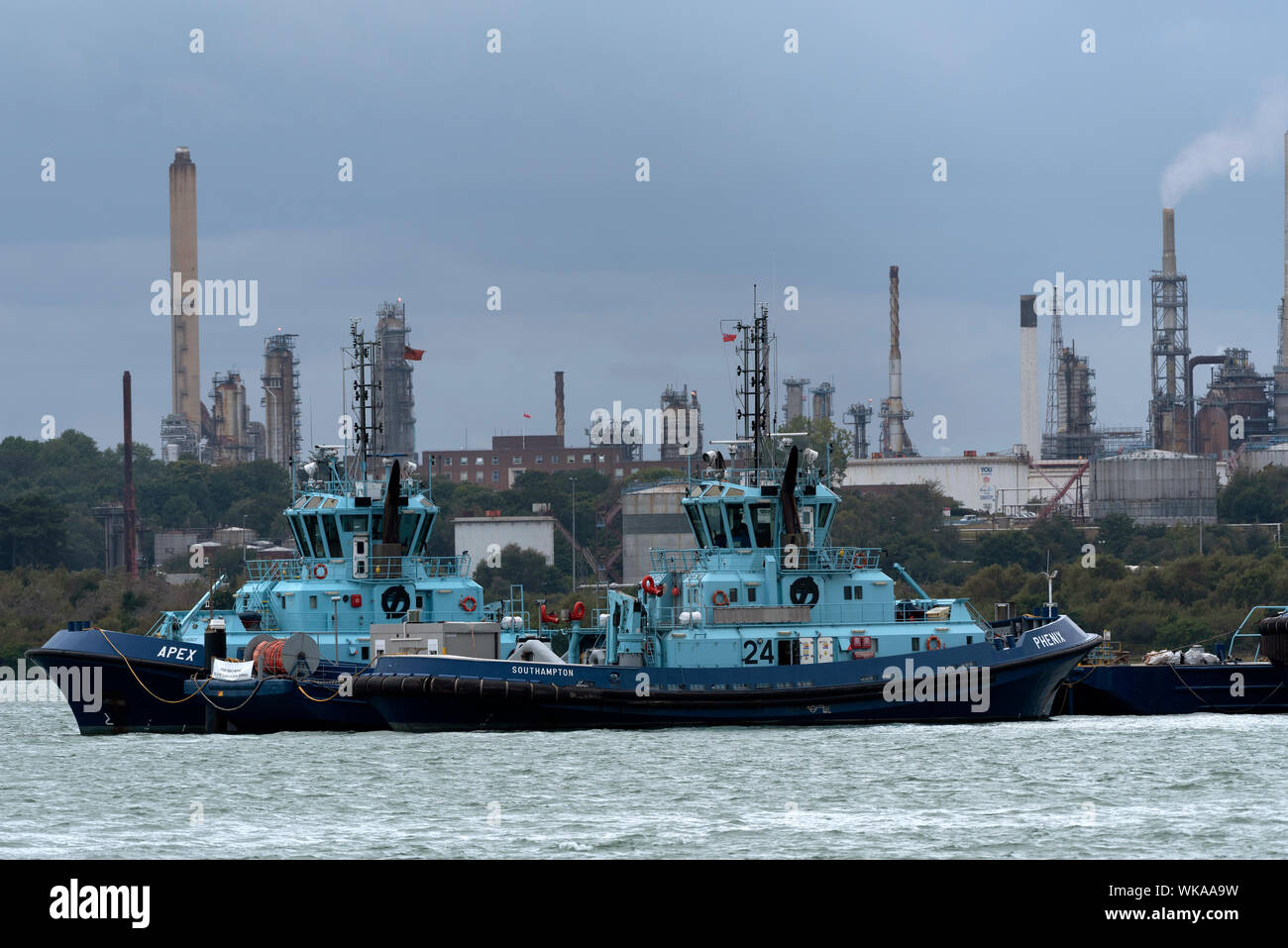 Fawley Marine, Southampton Water, England, UK. Apex and Phenix two Voith tractor tugs powered by Rolls Royce engines, alongside Fawley Marine refinery Stock Photo