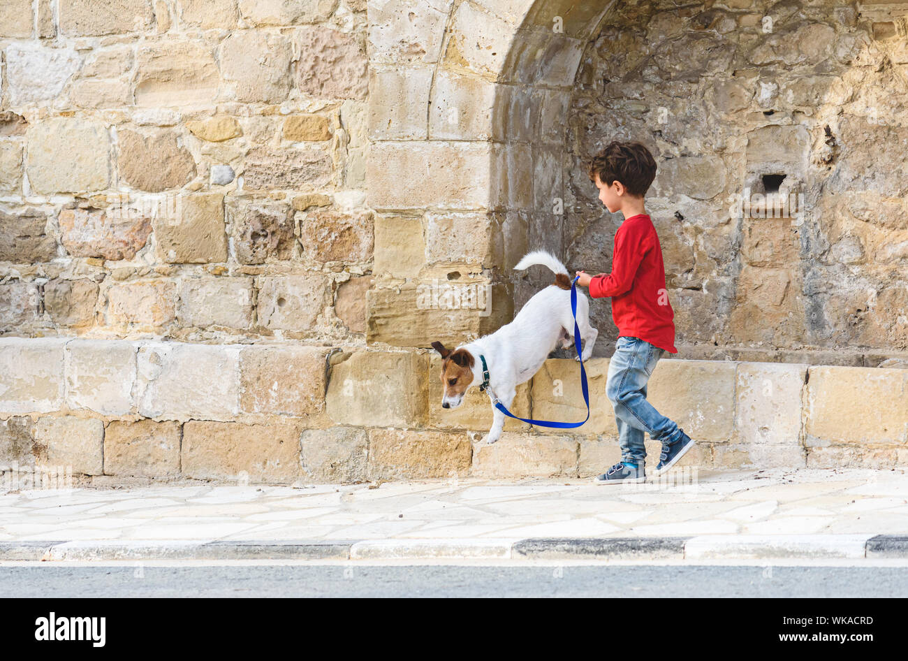 Kid walking with dog on leash at streets of old south town Stock Photo