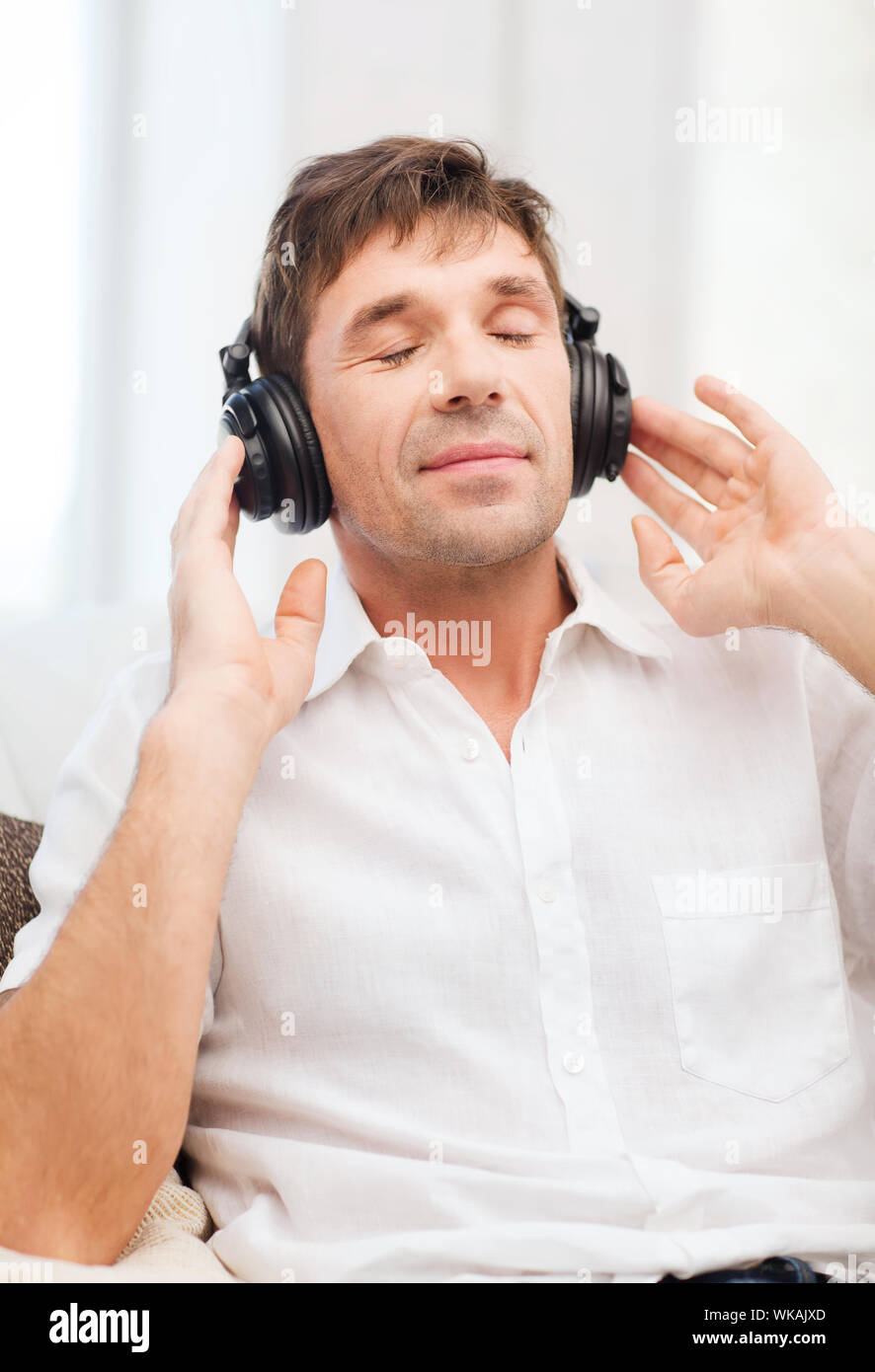 leisure and lifestyle concept - happy man with headphones listening to music at home Stock Photo