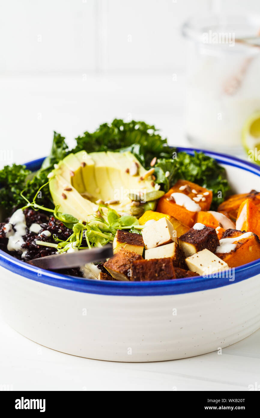 Buddha bowl salad with black rice, avocado, tofu, yam, kale and tahini