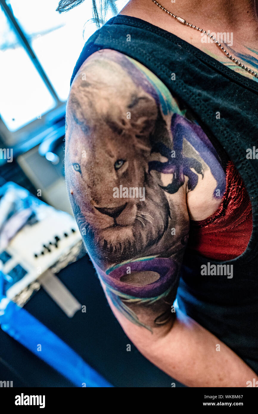 Midsection Of Woman With Lion Tattoo On Shoulder At Studio Stock Photo