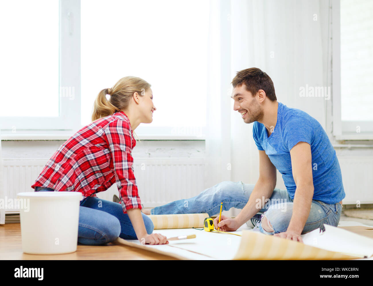smiling couple measuring wallpaper Stock Photo