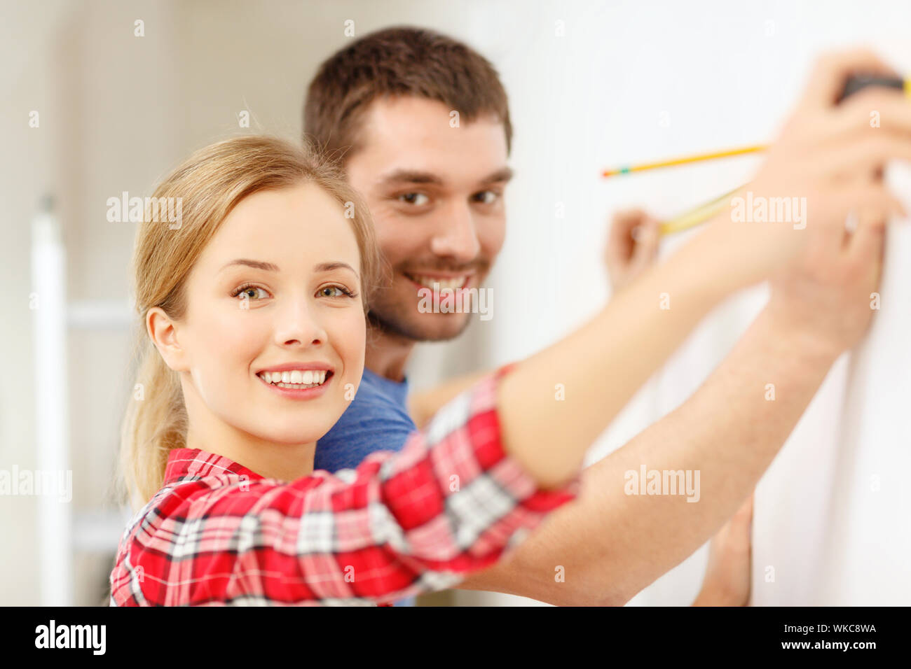 smiling couple measuring wall Stock Photo
