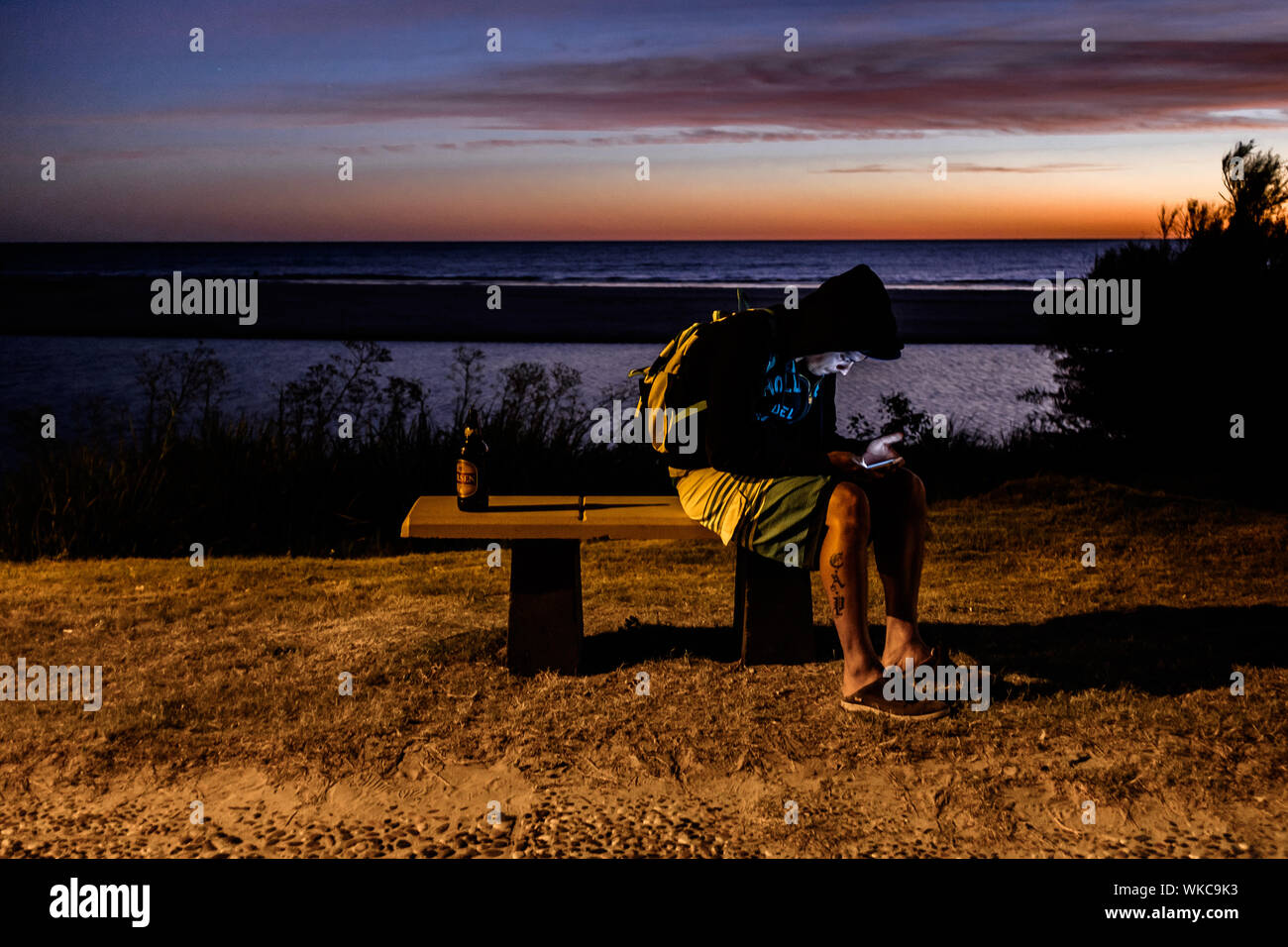 Uruguay: Uruguay, La Floresta, small city and resort on the Costa de Oro (Golden Coast). At dusk, a young boy is seated on a bench, facing the Rio de Stock Photo