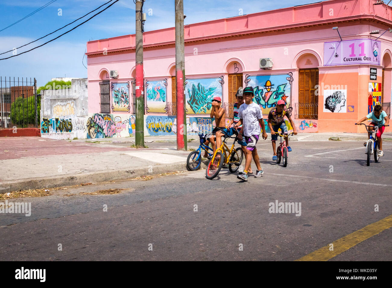 Uruguay, Montevideo: In the Cerro District, young boys with bikes playing in front of the cultural centre, with colourful graffiti on the facades Stock Photo