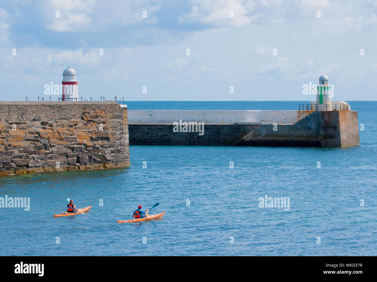 Sea kayakers paddling past the entrance to Laxey Harbour, Isle of Man Stock Photo