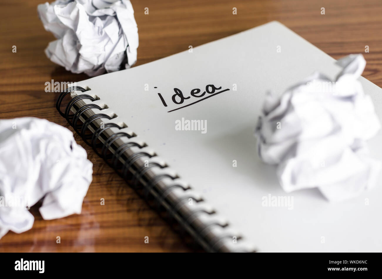 notebook write idea word with crumpled on wooden background Stock Photo