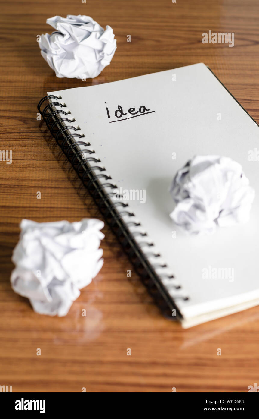 notebook write idea word with crumpled on wooden background Stock Photo