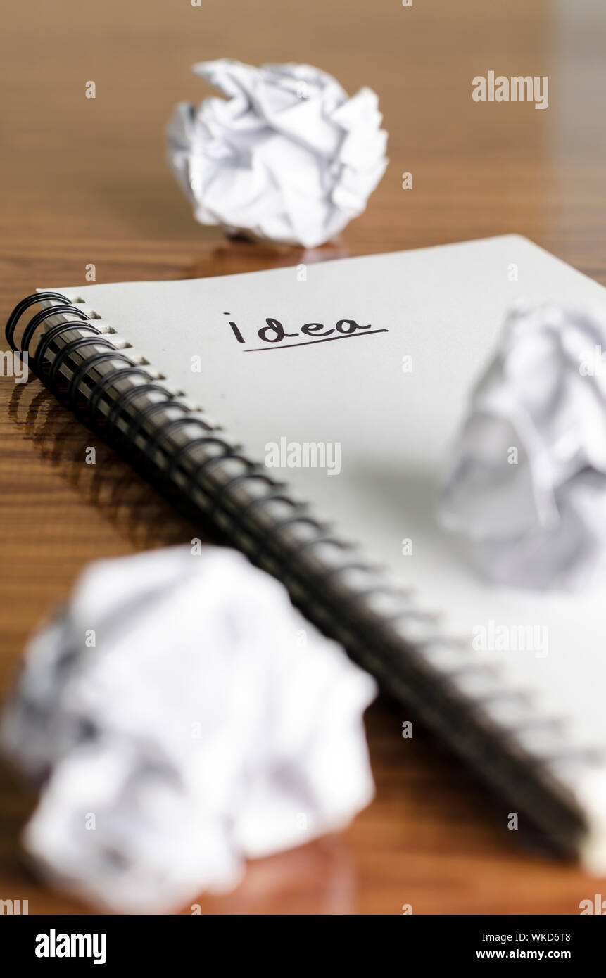 notebook write idea word with crumpled on wooden background Stock Photo