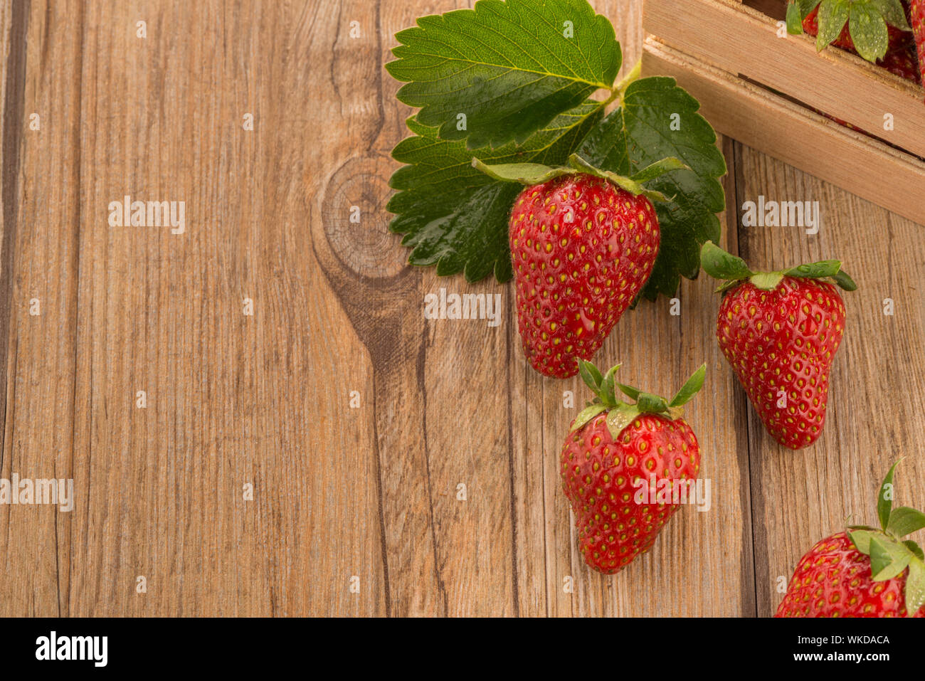 Strawberries over odl brown wooden table background Stock Photo - Alamy