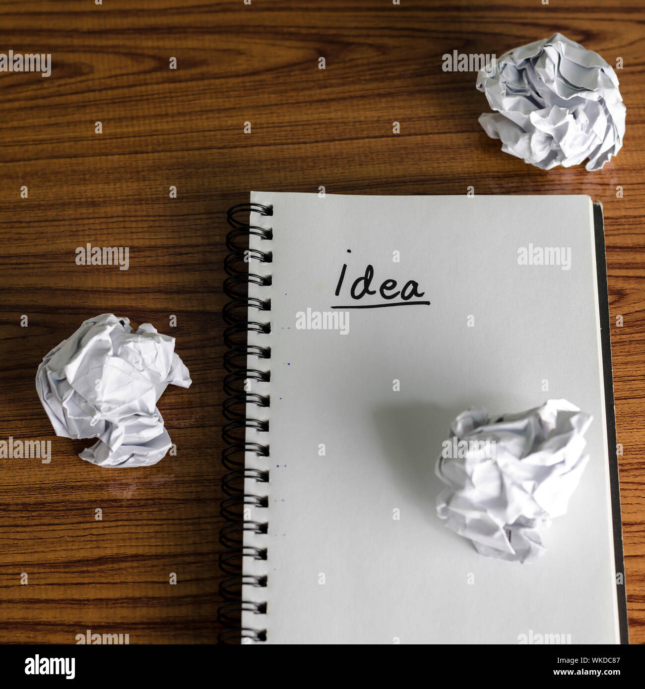 notebook write idea word with crumpled on wooden background Stock Photo