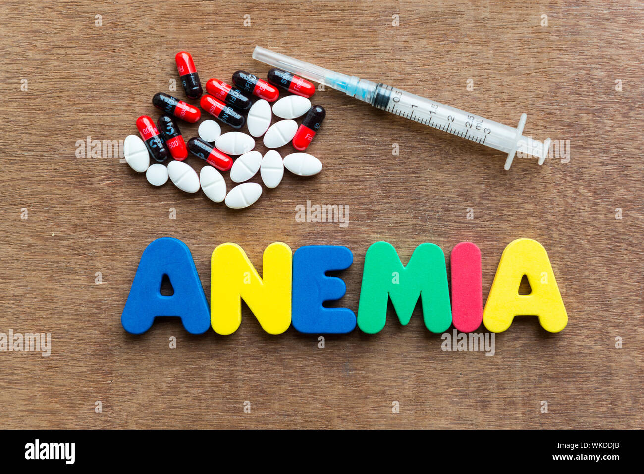 Close-up Of Multi Colored Anemia Text With Pills And Syringe On Table Stock Photo