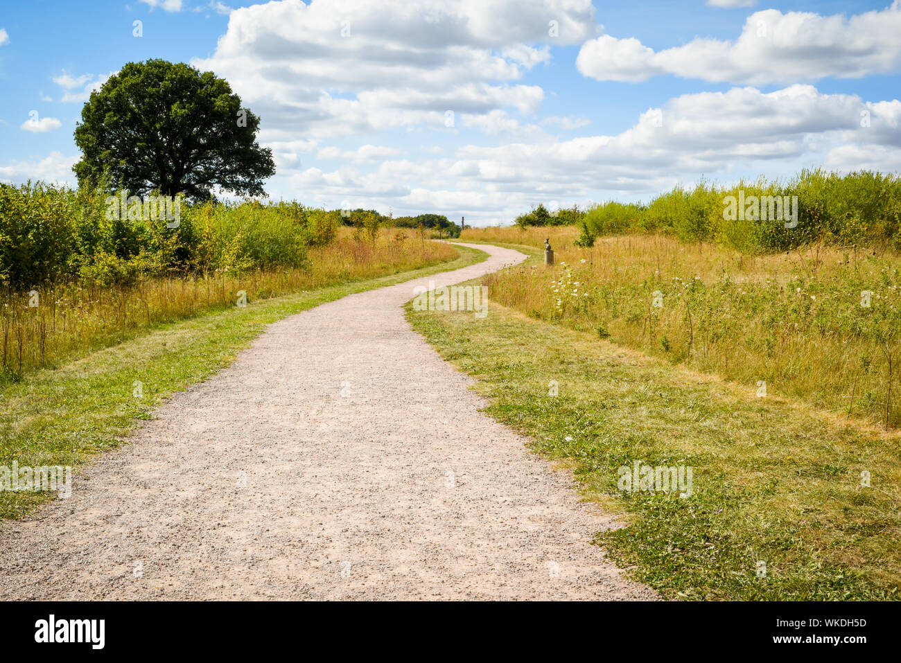 Long winding gravel footpath through a country field No people. view to horizon Stock Photo