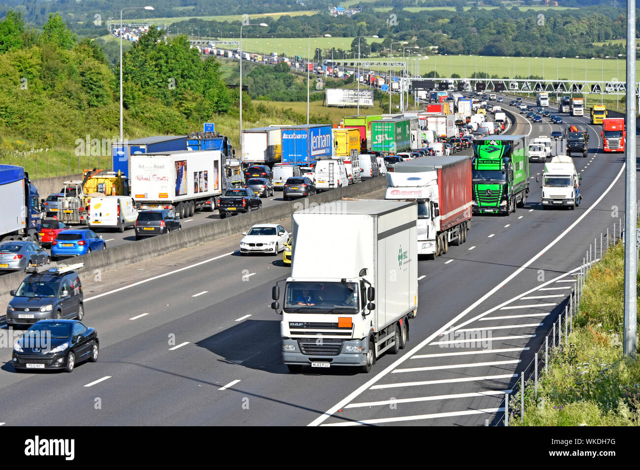 View from above of motorway countryside landscape with traffic jam on M25 & busy lorry truck movement on near side four lane section Essex England UK Stock Photo