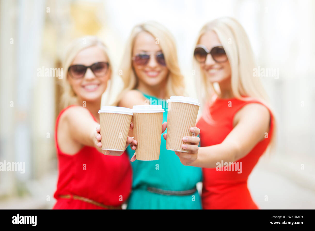 beverage and drink concept - three smiling blonds holding takeaway coffee cups in the city Stock Photo