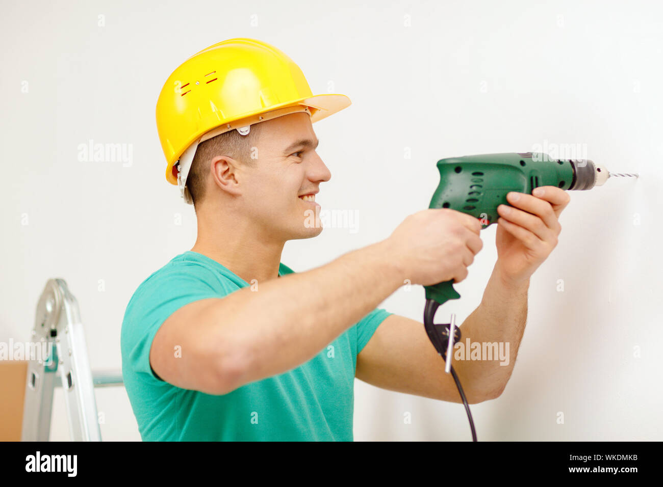 man with electric drill making hole in wall Stock Photo
