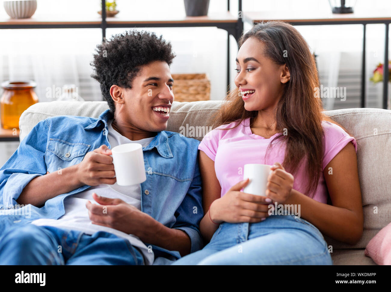 Guy and girl drinking coffee at home relaxing on sofa Stock Photo