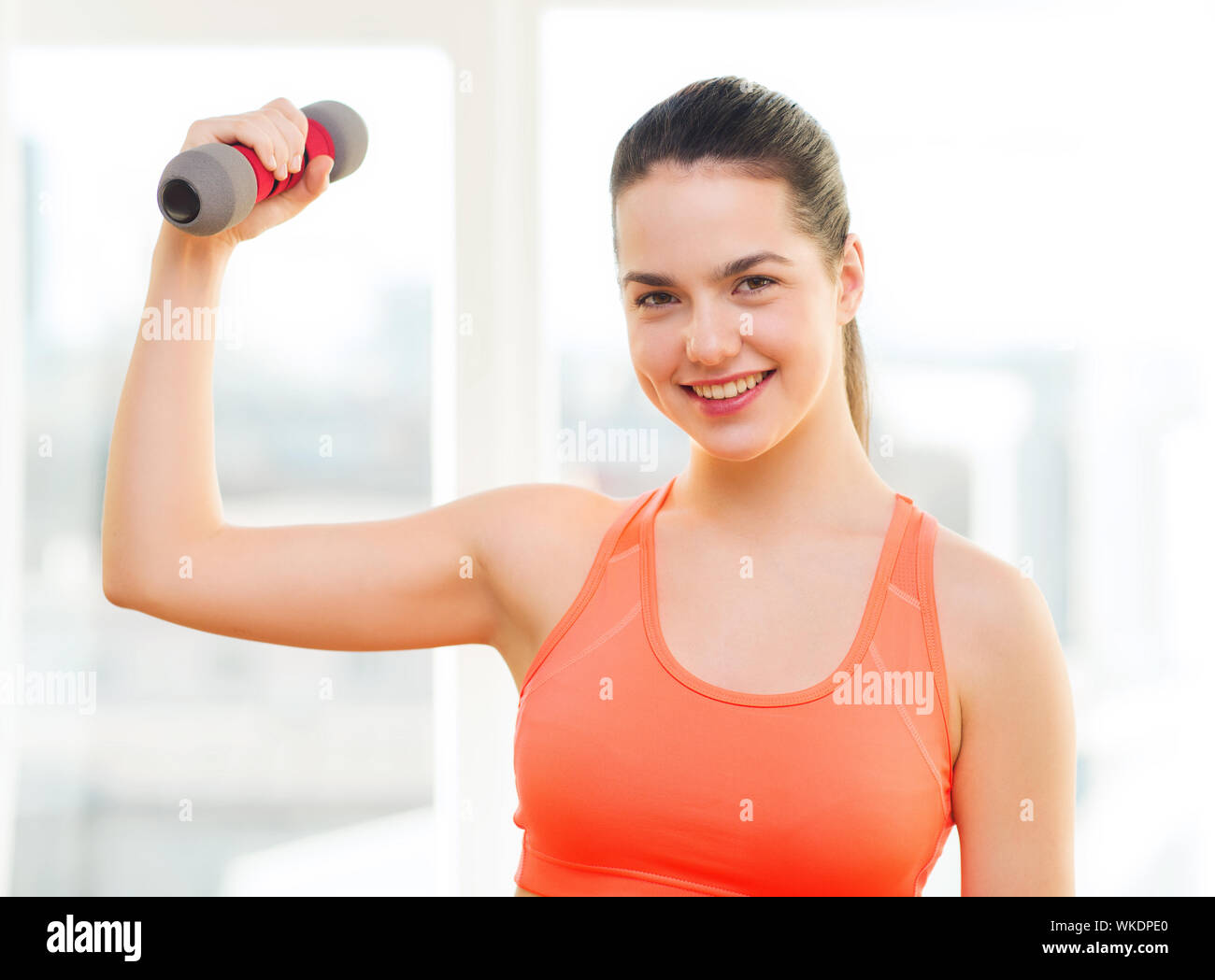 fitness, home and diet concept - smiling redhead girl exercising with heavy dumbbell at home Stock Photo