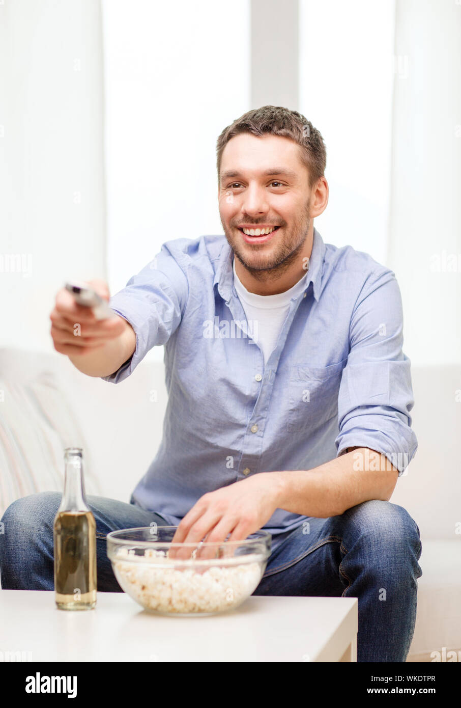 smiling man with tv remote control at home Stock Photo
