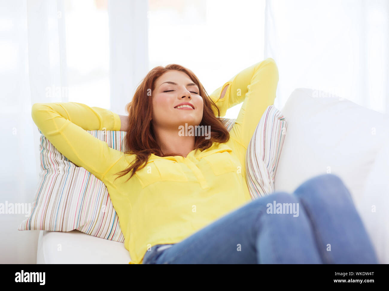 smiling young woman lying on sofa at home Stock Photo - Alamy
