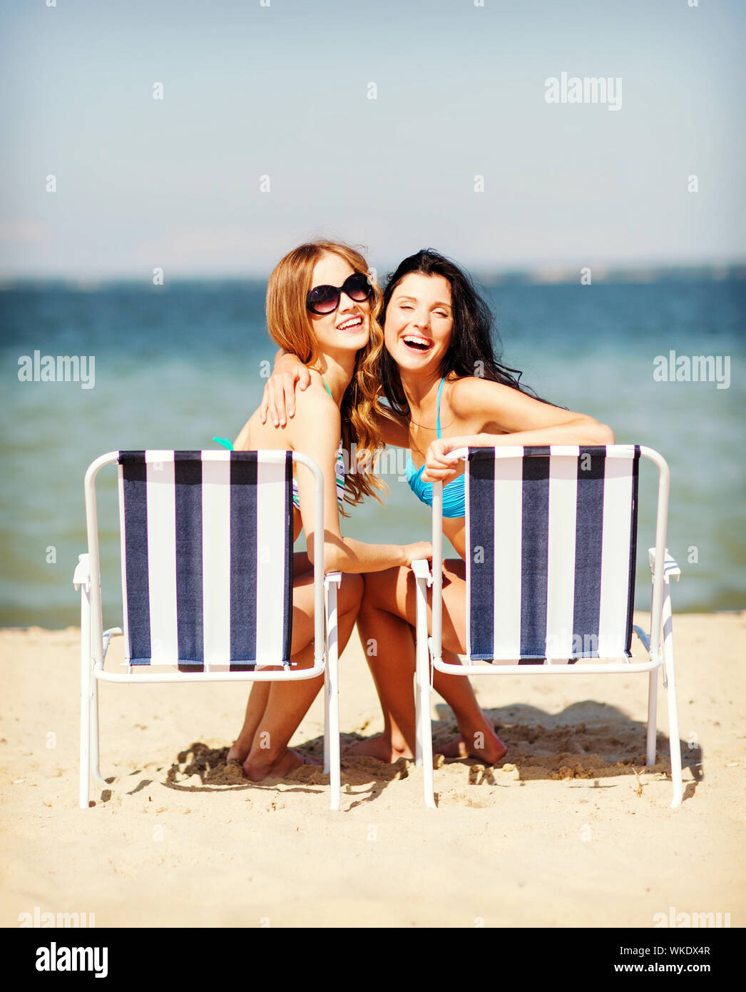 summer holidays and vacation girls in bikinis sunbathing on the beach chairs Stock Photo Alamy