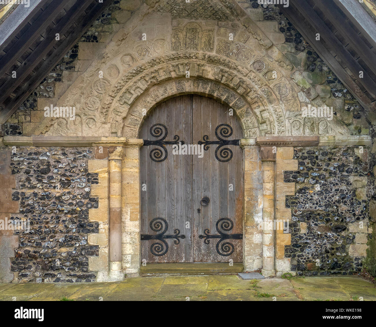 Old wooden door of a church.The wall has carvings over the archway.Part ...