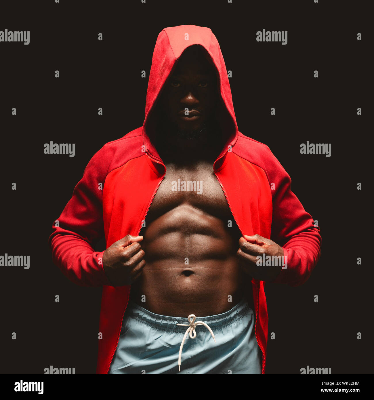 African american boxer in red hoodie over black studio background Stock