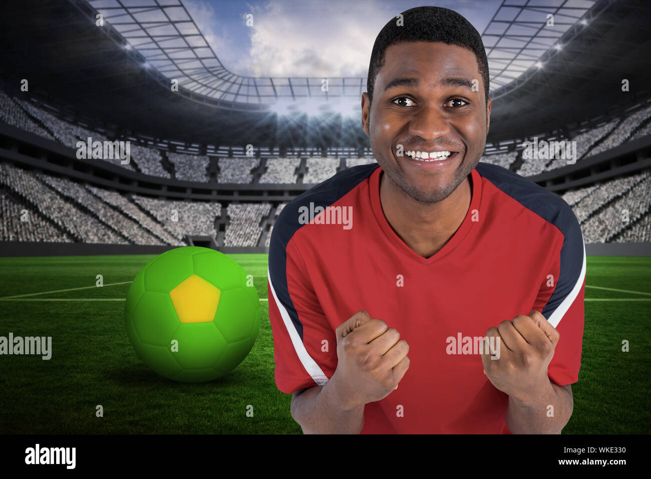 Excited handsome football fan cheering against vast football stadium