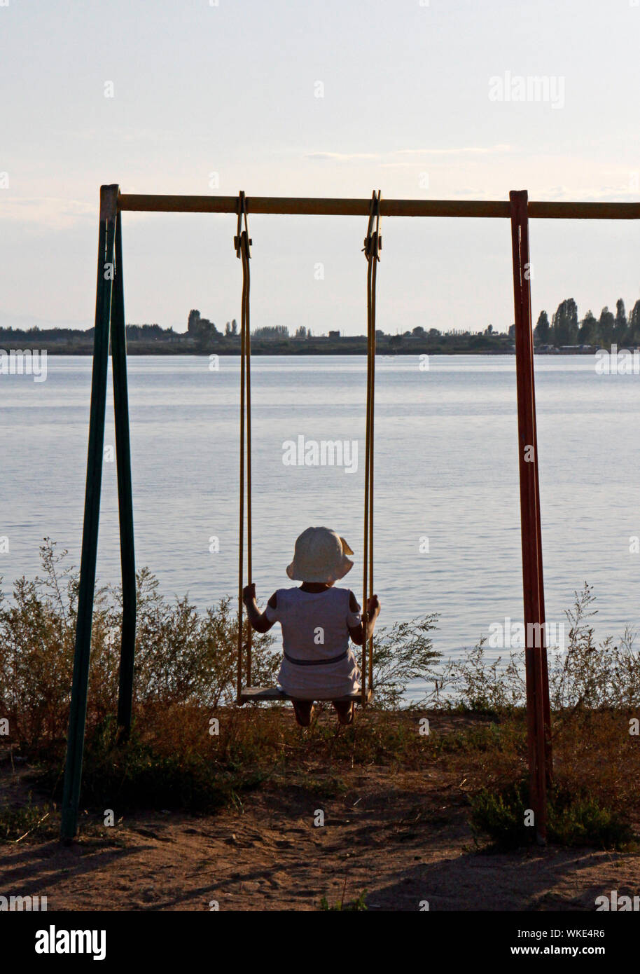Girl on a swing in front of Lake Issyk Kul in Kyrgyzstan Stock Photo