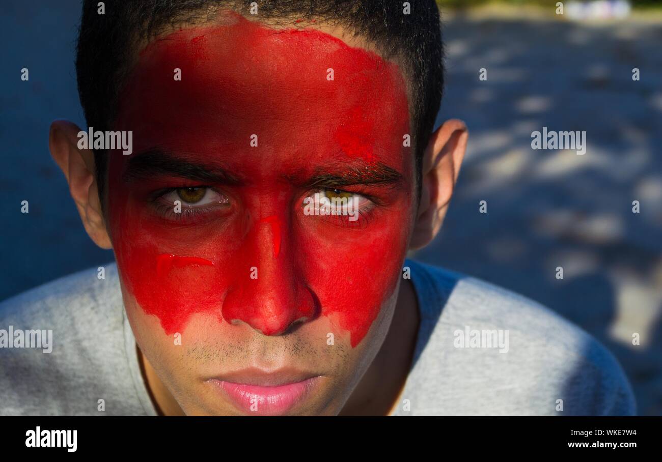 Close-up Portrait Of Young Man With Red Face Paint Stock Photo