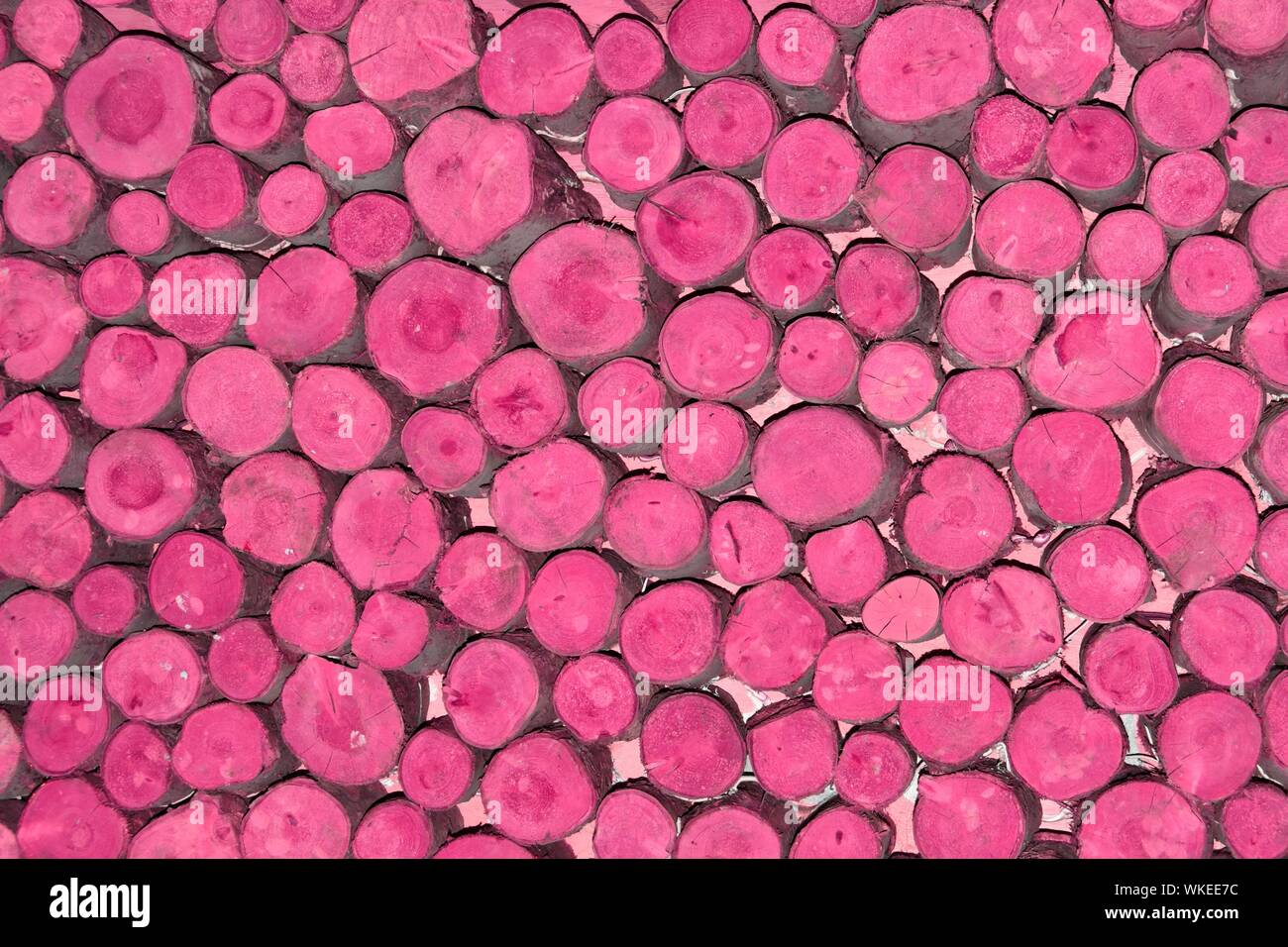 Abstract background pattern image manipulated pink colour applied to ends stacked short lengths of random diameter round sawn timber logs England UK Stock Photo