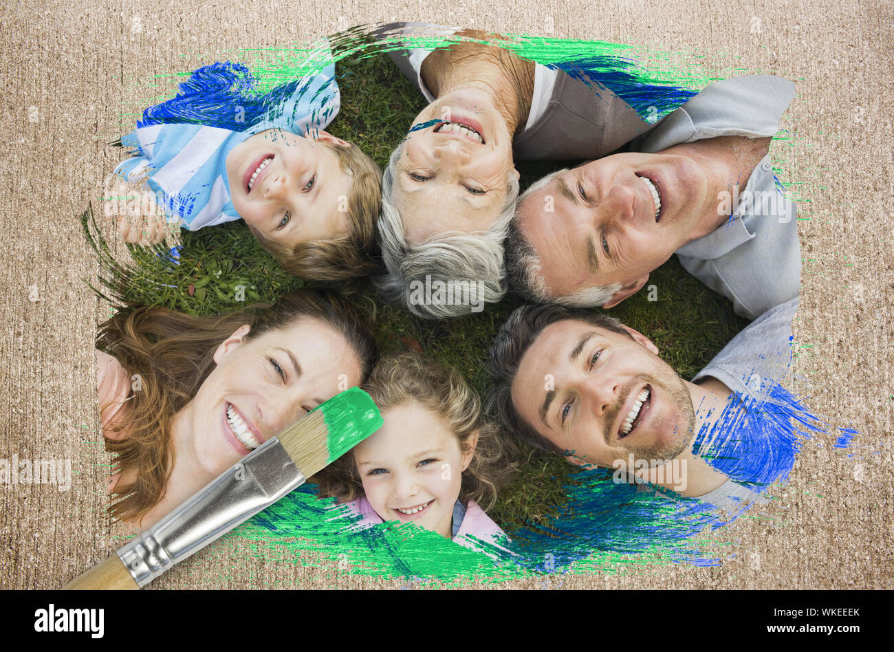 Composite image of extended family smiling at camera with paintbrush dipped in green against weathered surface Stock Photo