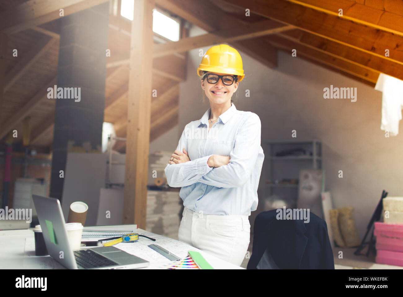 very pretty young female architect wearing yellow helmet is planning a loft in a house Stock Photo