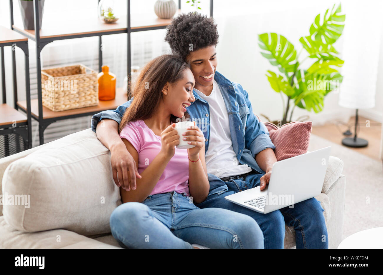 Smiling teenagers watching funny video on laptop at home Stock Photo