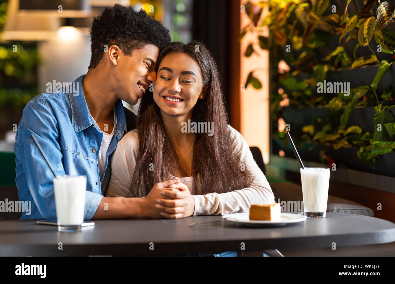 Sweet teen couple holding each other hands in cafe Stock Photo - Alamy