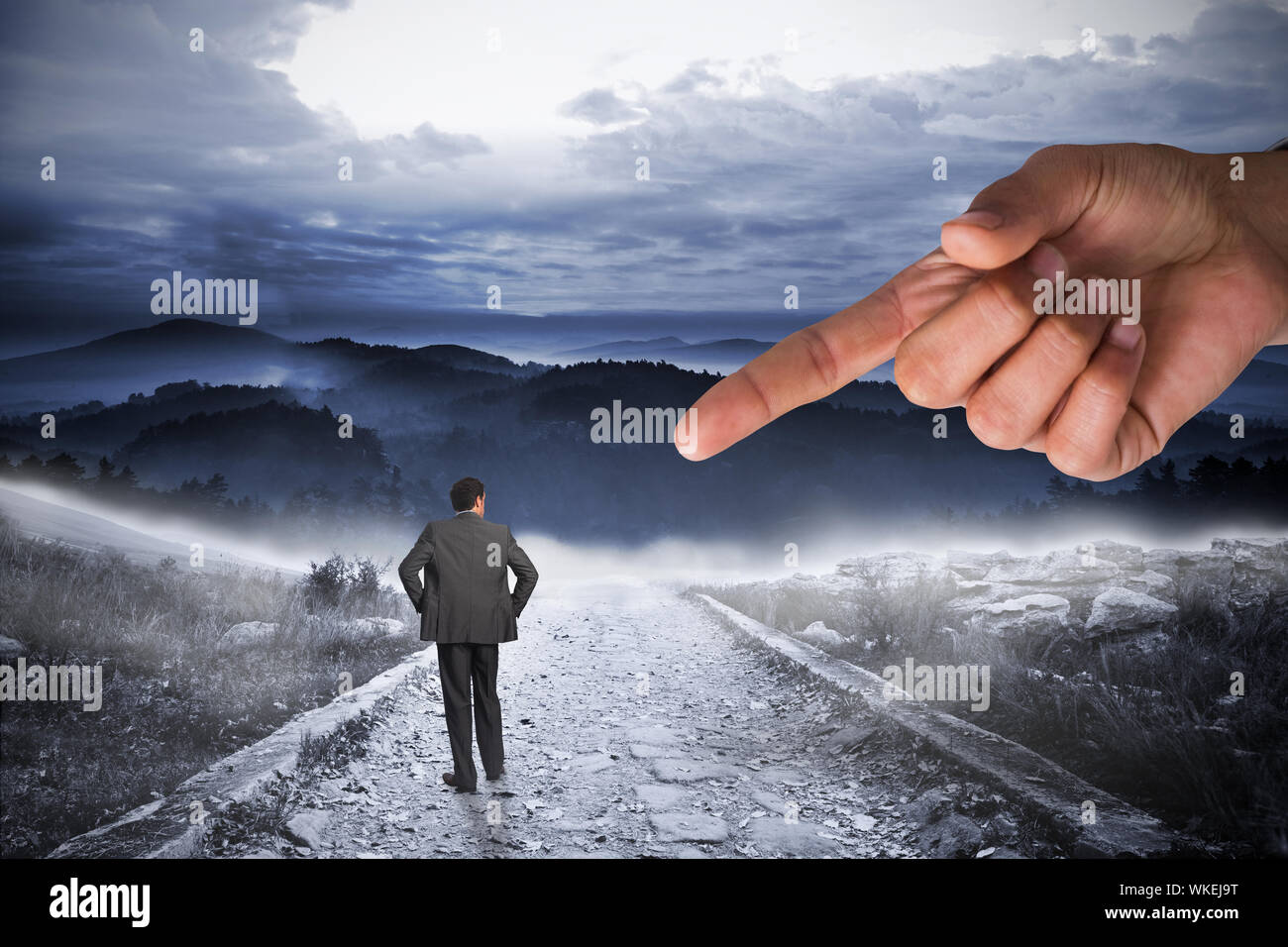 Giant hand pointing at businessman with hands on hips against stony