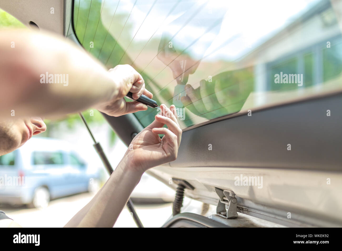 Close up shot hands of man removing old car window film Stock Photo